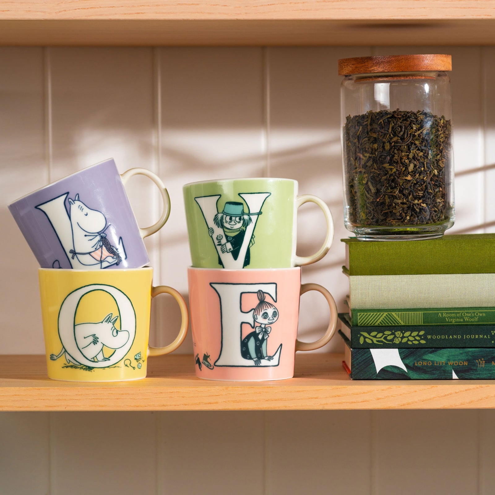A collection of Moomin Arabia Alphabet mugs on a kitchen shelf